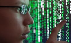 A young man with glasses is watching futuristic symbols on a computer screen