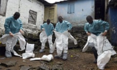 Medical staff put on protective suits before collecting the corpse of a victim of Ebola, in Monrovia.