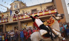 A rider on a horse back rips the head off a goose, hanging by its feet on the feast day of Santiago, Spain
