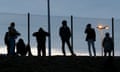 Migrants are seen in silhouette as they stand on a rise near a fence as they gather near the Channel Tunnel access in Frethun, near Calais, France.