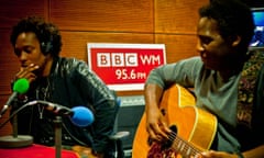 Lemar, with headphones on, and Angelo Starr, with a guitar, in a recording studio