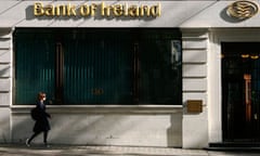 A woman passes a branch of the Bank of Ireland in London