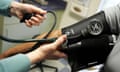 A doctor reads a patient's blood pressure gauge