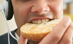 A man listening to music and eating a bagel