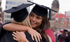 A young woman on graduation day hugging her fellow graduate.