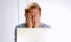 Young man in front of his laptop computer with head in hands