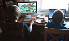 Two boys playing the video game Minecraft at home on computers.