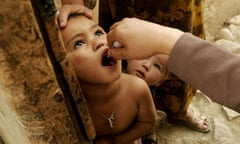 Health worker administers a polio vaccination to a child at their house in Kabul, Afghanistan