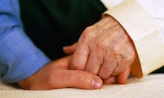 Dementia carer holding hands with patient