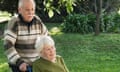 Man pushing his disabled wife's wheelchair in a garden