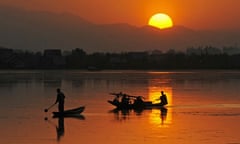 Kashmiris ride a boat during a sunset at