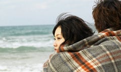 Couple at the beach wrapped in a blanket