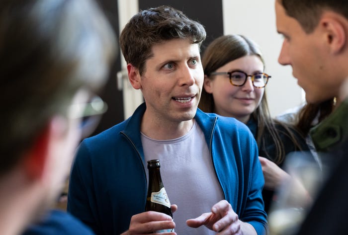Sam Altman, wearing a blue jacket and holding a beer bottle, chats with audience members at the Technical University of Munich (TUM) after a panel discussion