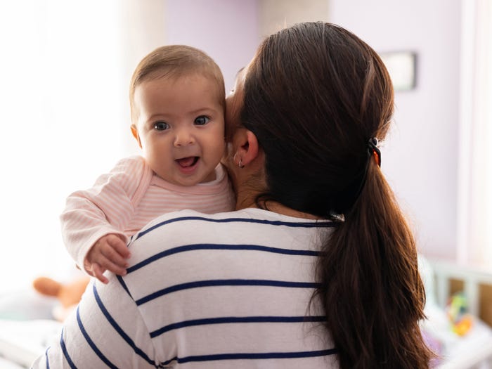 Baby smiling while her mother is carrying her at home