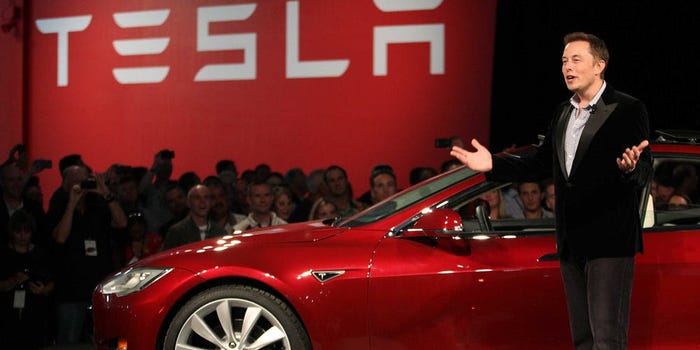 elon musk in front of a red Tesla