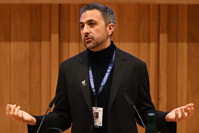 Mustafa Suleyman wearing a black blazer and polo neck sweater