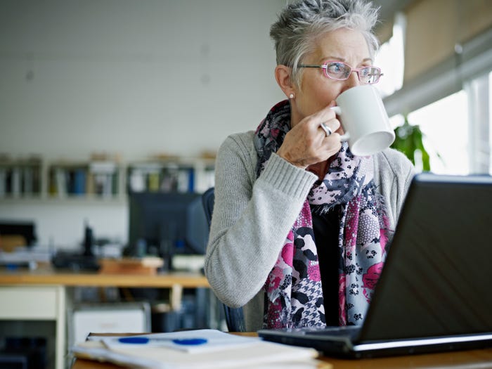 A woman sitting in office drinking coffee.