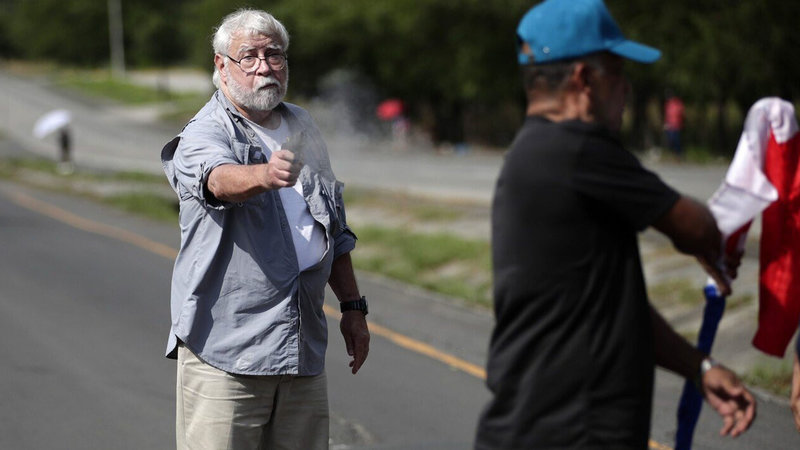 An image of the American Panama climate activist shooter firing a pistol toward another man.