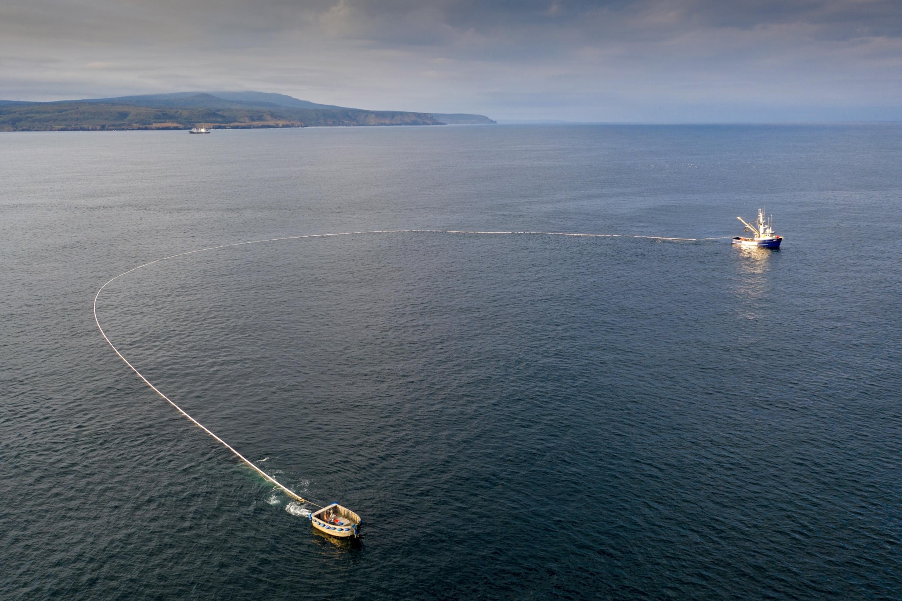 two boats dragging a very long net