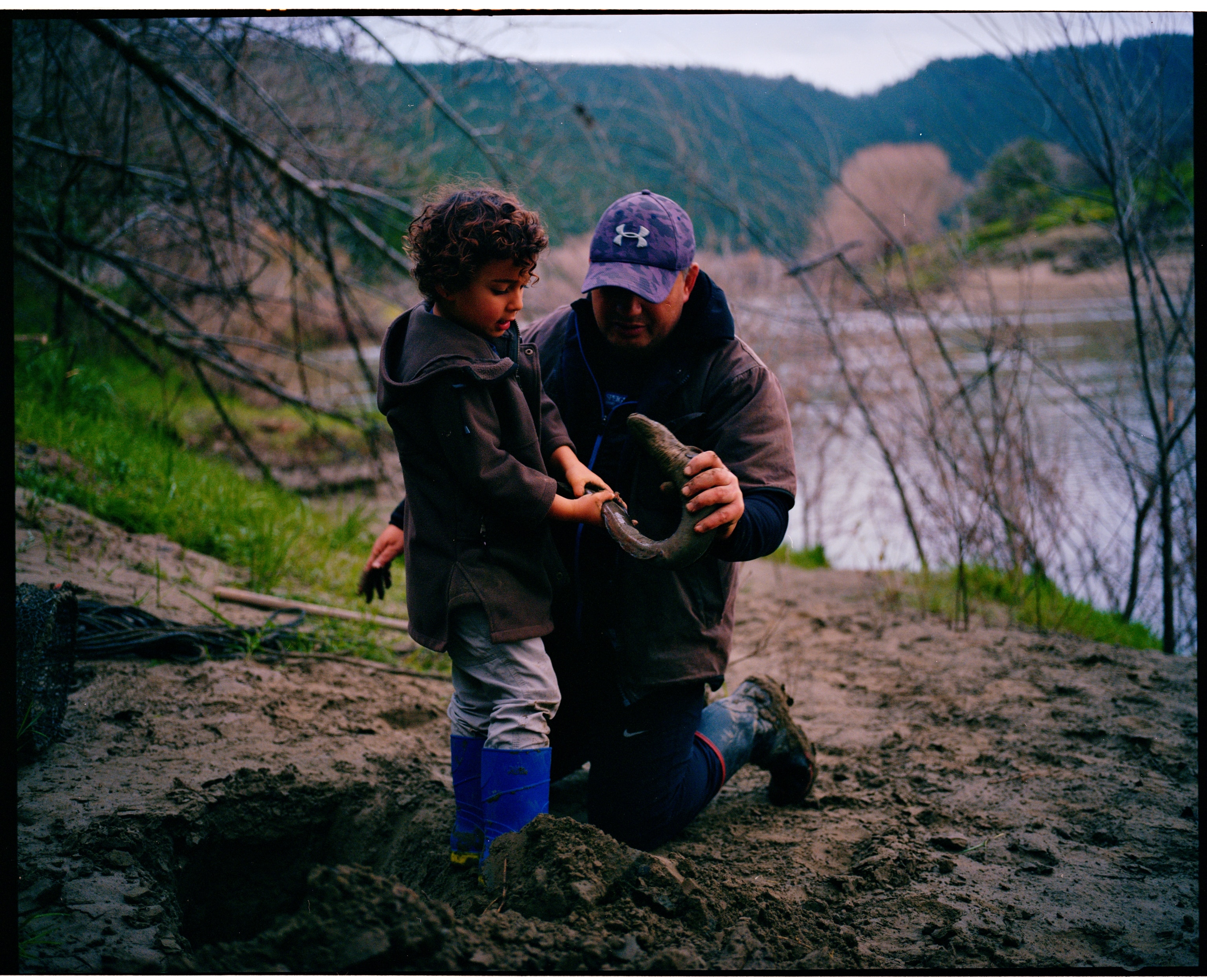 A man teaches his son how to catch eels along the Whanganui River, New Zealand