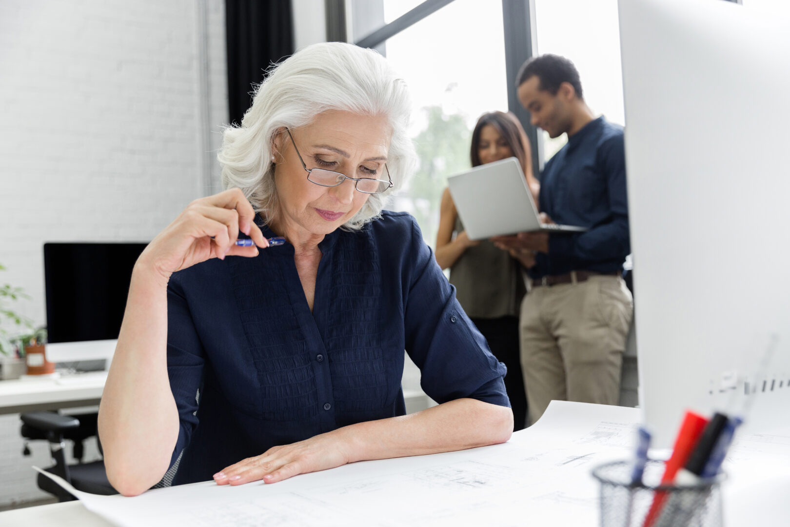 Mature business woman working with documents while sitting at her workplace in an office