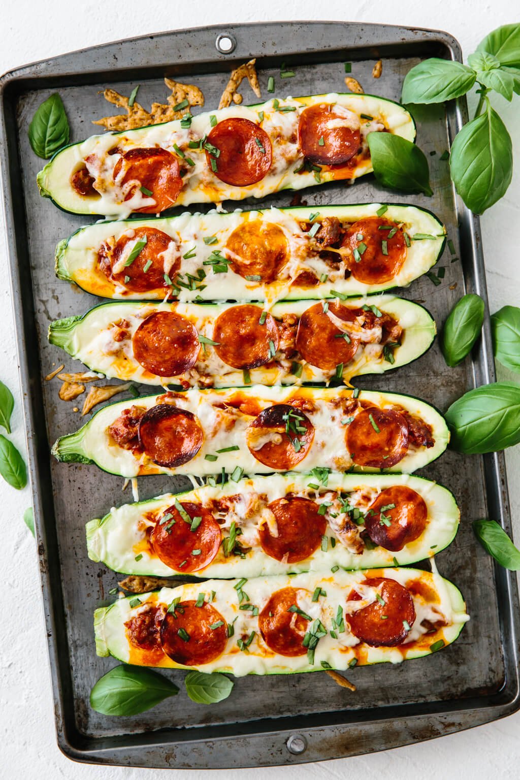 Pizza stuffed zucchini on a baking tray.