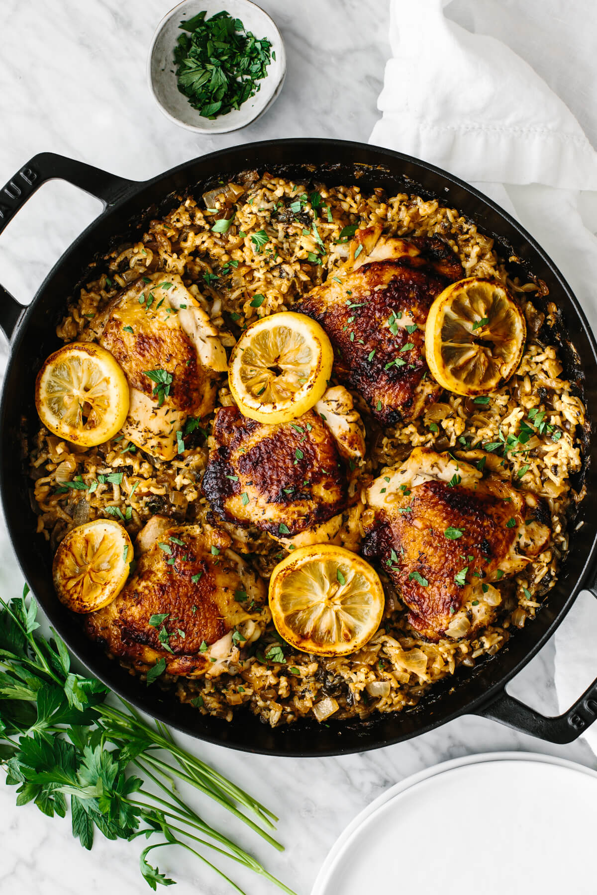 Chicken and rice in one pan garnished with lemon slices and parsley.