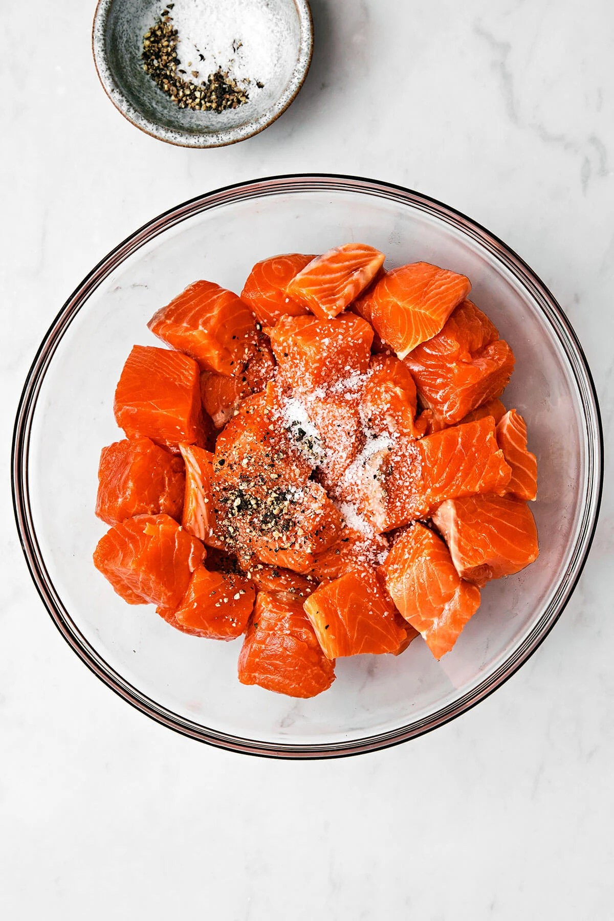 Mixing salmon cubes with salt and pepper in a bowl