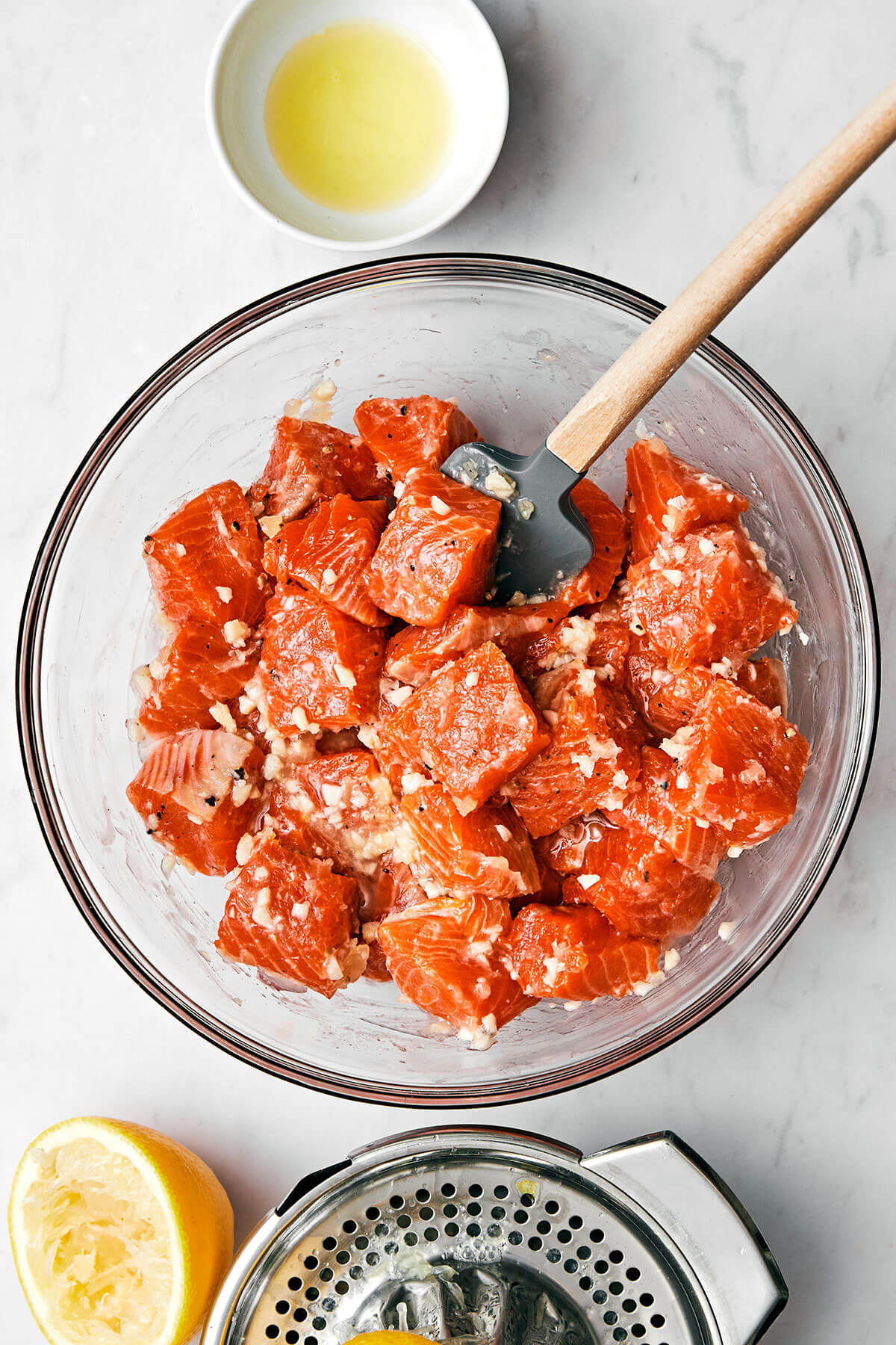 Mixing salmon cubes in sauce in a bowl