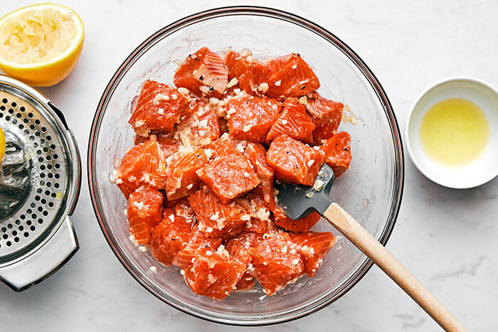 Mixing salmon cubes with a sauce