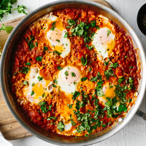 Shakshuka in a pan with fresh herbs on top.