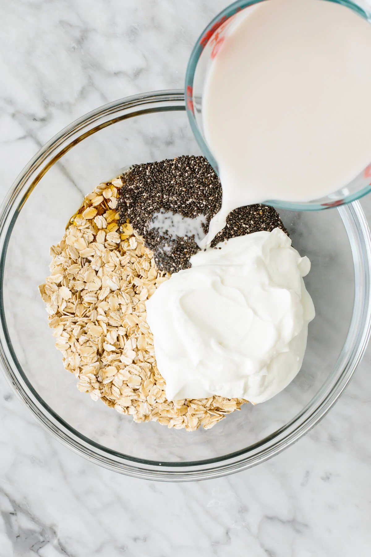 Adding overnight oats ingredients to a large bowl.