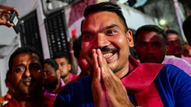 Night time shot of Namal Rajapaksa smiling with his hands together in front of his face, while at an election rally in Colombo on September 16, 2024.