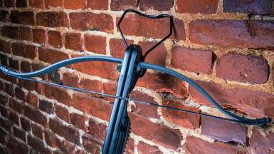A crossbow resting against a brick wall