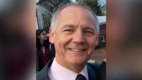 A headshot of Paul Taylor. He is wearing a pink shirt and tie.