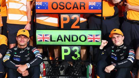 Lando Norris (left) and Oscar Piastri pose with a sign showing their finishing positions in the Italian Grand Prix