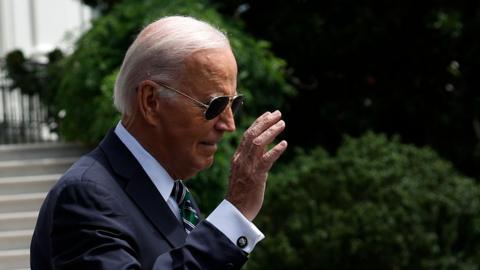 Joe Biden walking while wearing sunglasses 