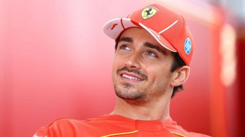 Charles Leclerc smiles and looks up