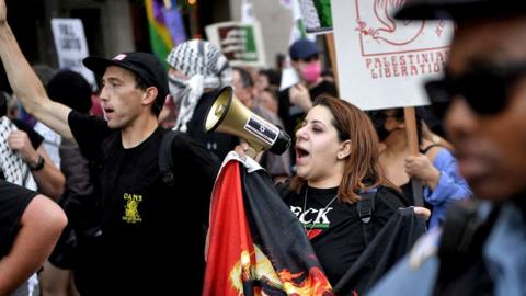 A woman speaks into a megaphone during a protest to demand a ceasefire in Gaza on the eve of the Democratic National Convention (DNC) at the United Center in Chicago, Illinois, on 18 August 2024