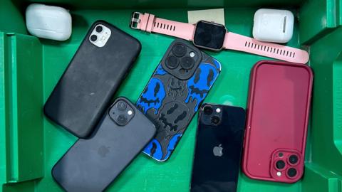 Smartphones, smart watches and Airpods in green tray