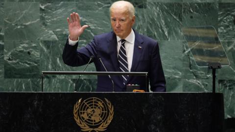 Joe Biden in blue suit at podium with UN logo in front of green marble wall