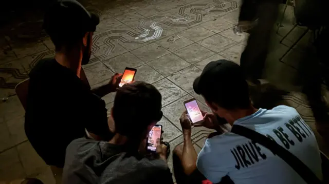 Three people looking at their mobile phones