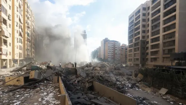 People can be stood amid debris, with smoke rising as high as the multi-storey buildings either side