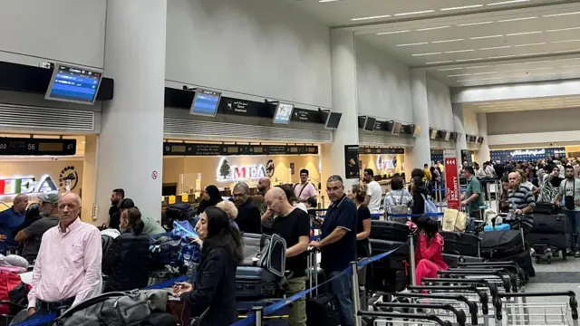 A long queue of people with luggage is seen in Beirut airport.