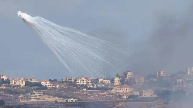 Smoke and rocket fire can be seen over structures in southern Lebanon