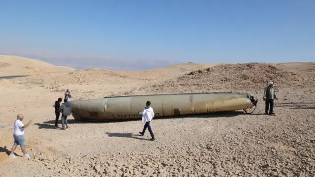 eople look at the wreckage of an Iranian ballistic missile in the Negev desert near the Dead Sea, southern Israel