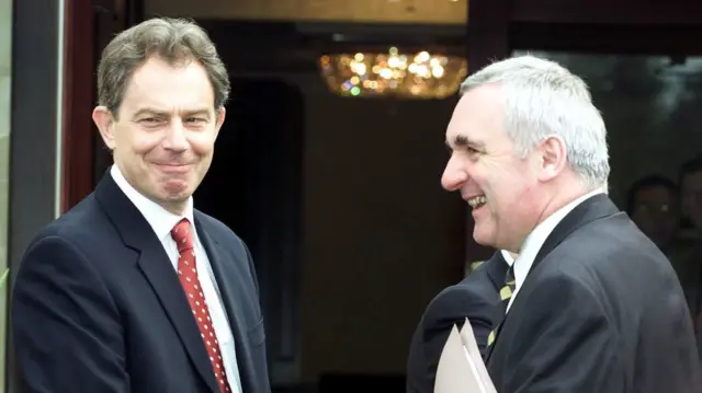 Taken in April 2021, the image shows Tony Blair (left) looking at the camera and smiling, and Bertie Ahern (right) smiling at Blair.