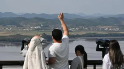 Visitors use binoculars to look at the North Korean side of the Demilitarised Zone (DMZ) dividing the two Koreas, from South Korea's Odusan Unification Observatory in Paju on October 9, 2024. 