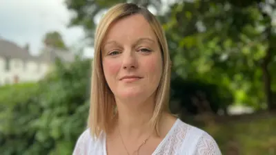 woman stands in front of bushes