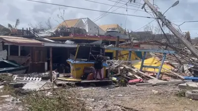 Una mujer frente a su casa de madera destrozada por el huracán